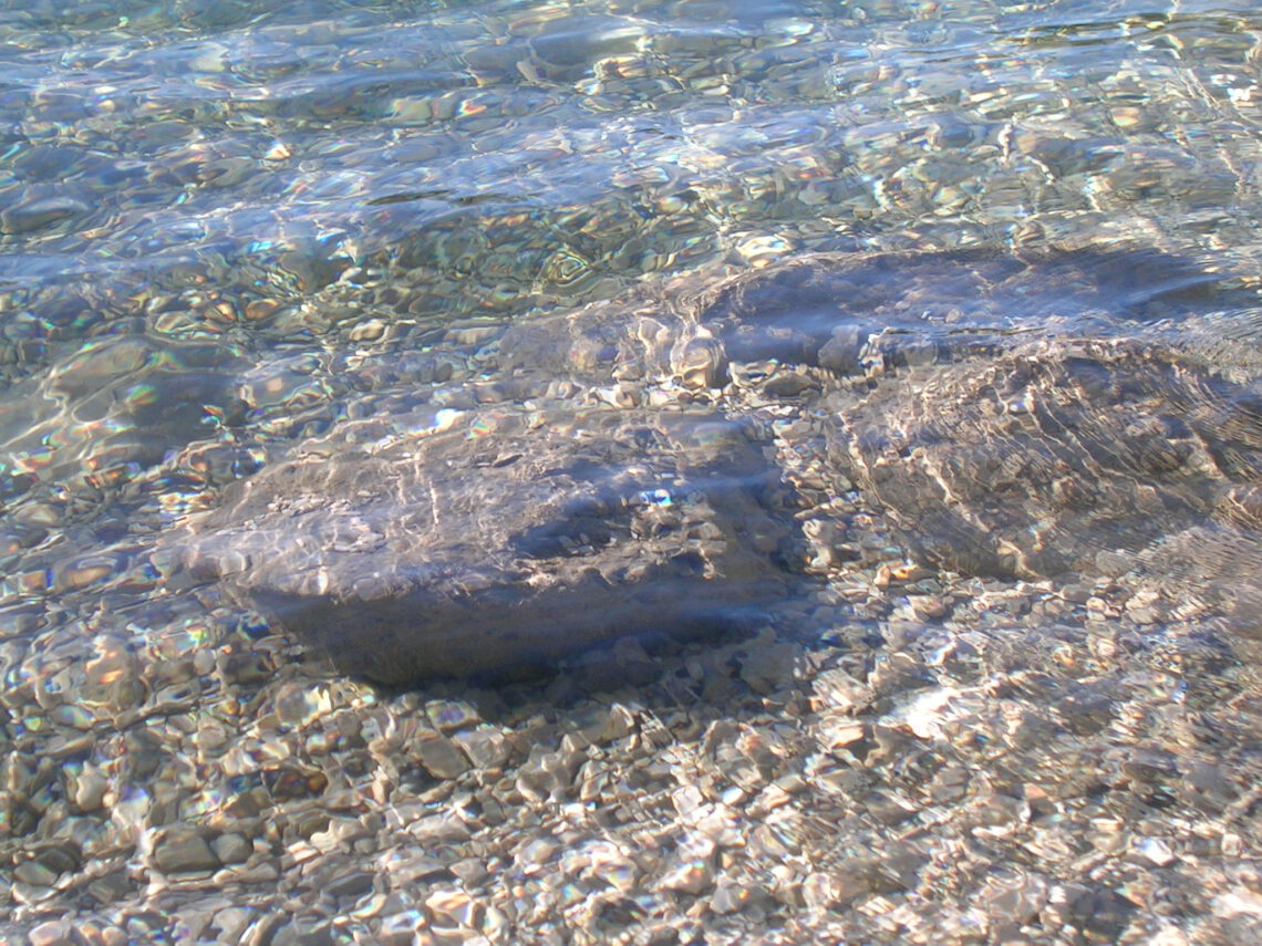 Ein großer Stein ist im klaren Wasser zu sehen.